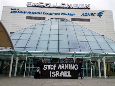 Protesters hold a "Stop Arming Israel" banner in front of the ExCeL centre