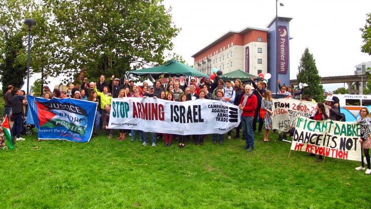 A crowd of protesters behind Stop Arming Israel banners